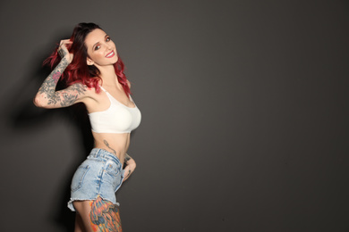 Beautiful woman with tattoos on body against black background. Space for text