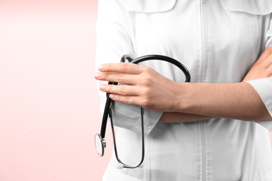 Photo of Doctor with stethoscope on pink background, closeup. Medical service