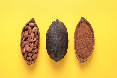 Cocoa beans, powder and pods on yellow background, flat lay