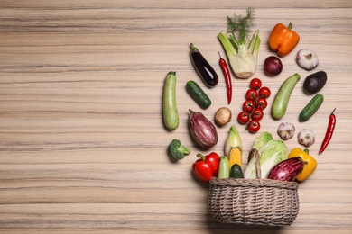 Photo of Flat lay composition with different vegetables and wicker basket on wooden background. Space for text