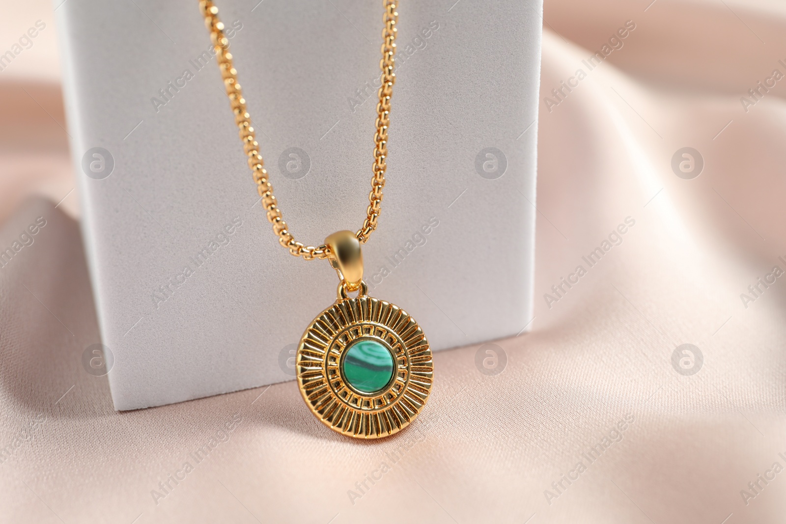 Photo of Stylish presentation of elegant necklace on beige cloth, closeup