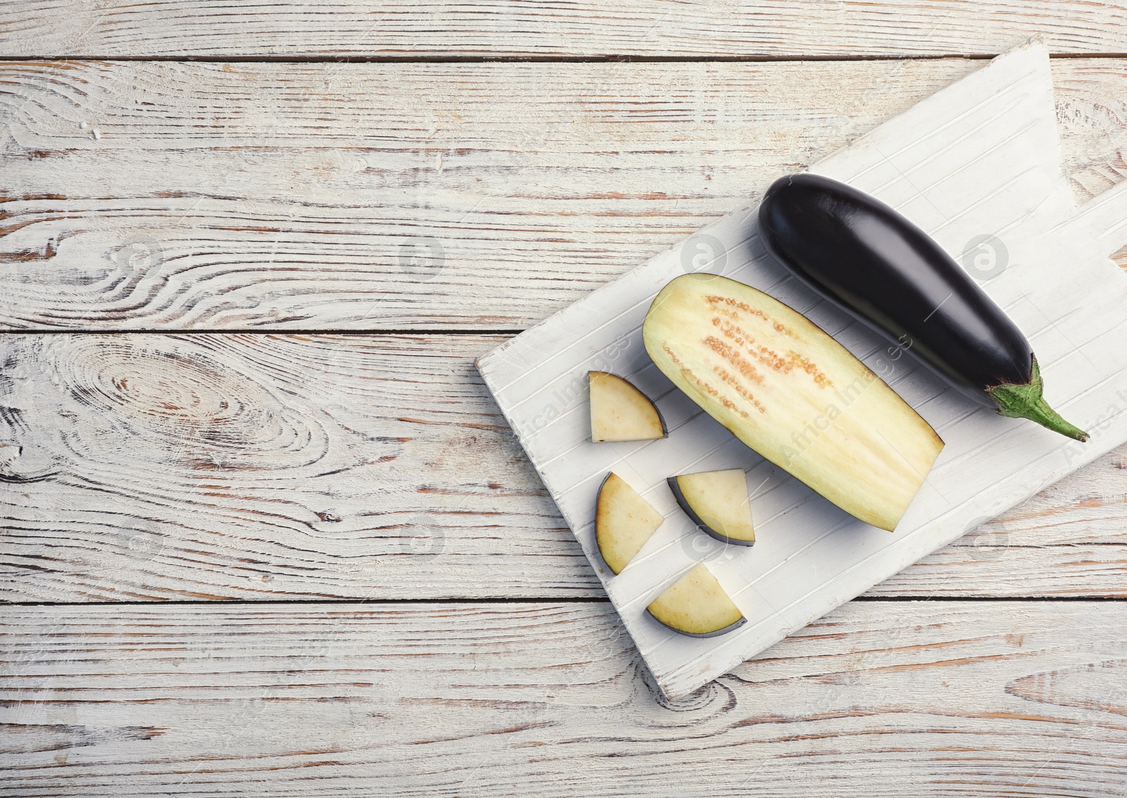 Photo of Board with ripe eggplants on wooden background, top view