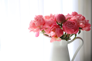 Beautiful bouquet of fragrant peonies in vase near window