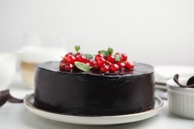 Photo of Tasty homemade chocolate cake with berries and mint on white table