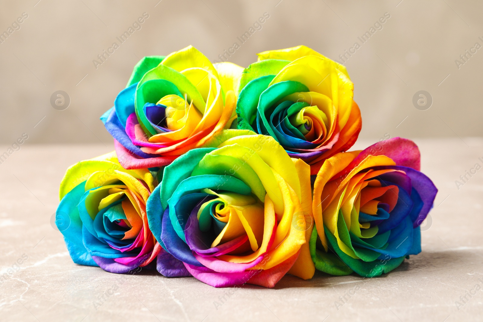 Photo of Amazing rainbow rose flowers on table