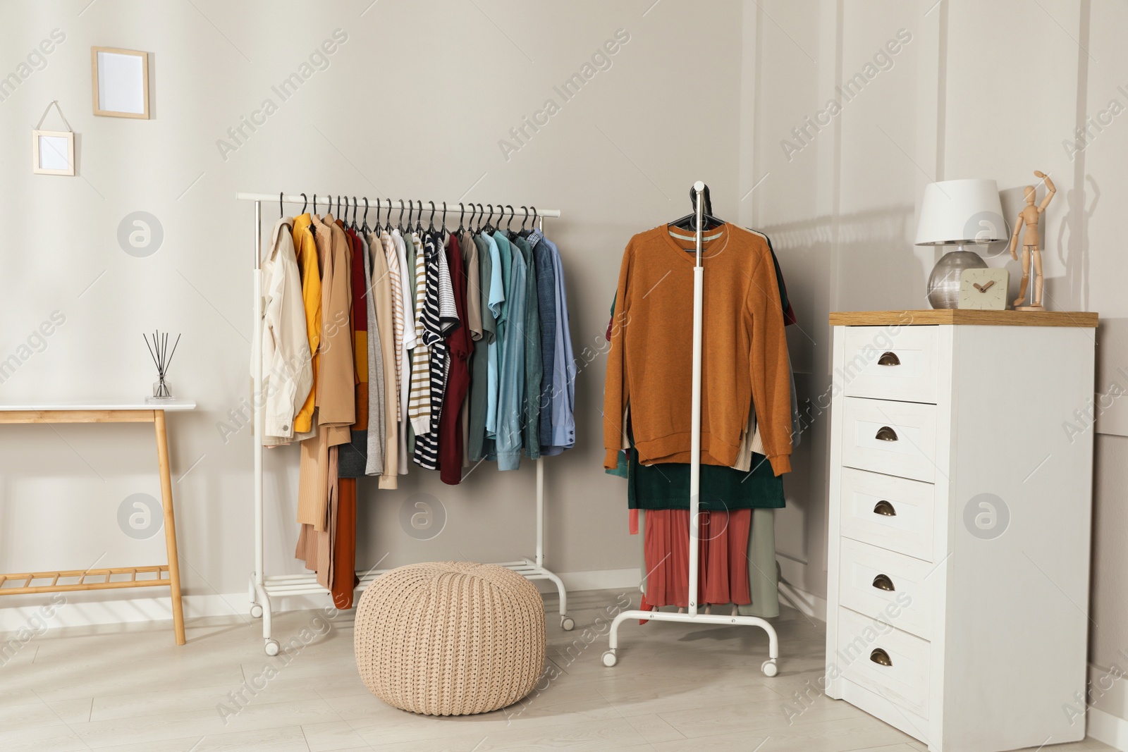 Photo of Racks with stylish clothes in cozy room interior. Fast fashion