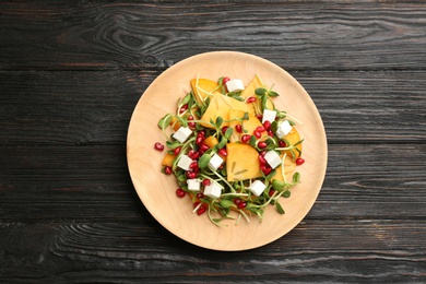 Photo of Delicious persimmon salad with pomegranate and feta cheese on wooden table, top view