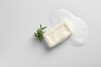 Photo of Soap bar, rosemary and foam on white background, top view