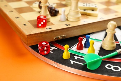 Photo of Different types of board games and its' components on orange background, closeup