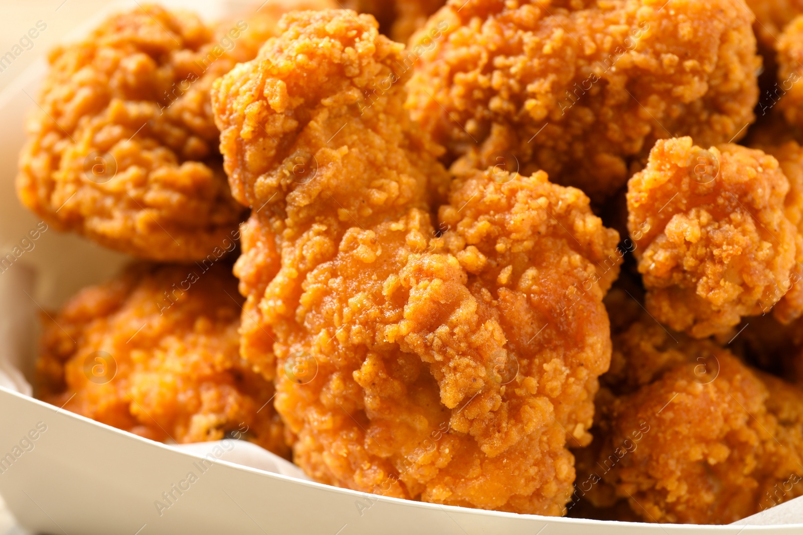 Photo of Tasty deep fried chicken pieces in cardboard box, closeup view