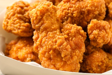 Photo of Tasty deep fried chicken pieces in cardboard box, closeup view