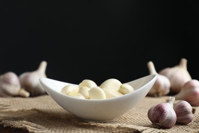 Photo of Fresh garlic cloves and bulbs on table against black background