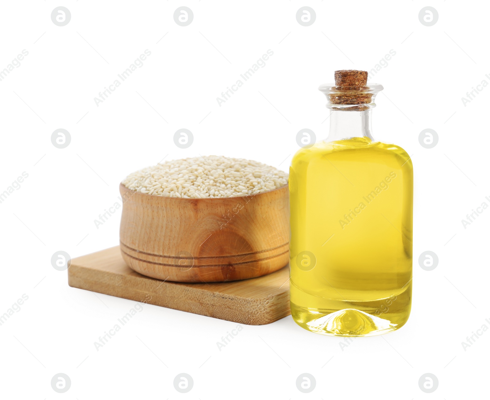 Photo of Glass bottle of fresh sesame oil and bowl with seeds isolated on white