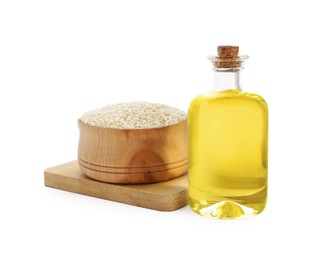 Photo of Glass bottle of fresh sesame oil and bowl with seeds isolated on white