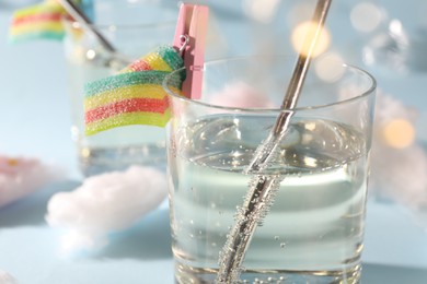 Photo of Tasty cocktail in glass decorated with gummy candy on light blue background, closeup