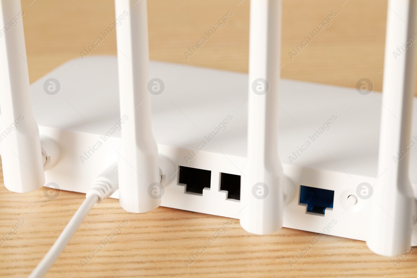 Photo of New white Wi-Fi router on wooden table, closeup