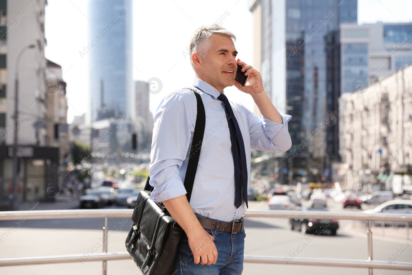 Photo of Handsome businessman talking by mobile phone in city