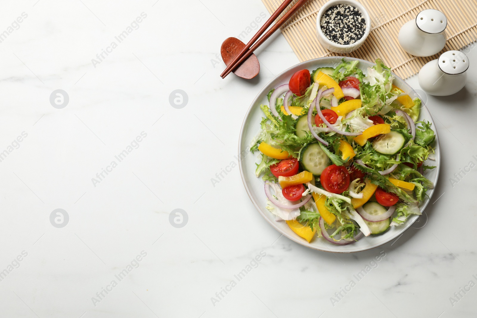 Photo of Tasty fresh vegetarian salad and chopsticks on white marble table, top view. Space for text