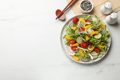 Photo of Tasty fresh vegetarian salad and chopsticks on white marble table, top view. Space for text