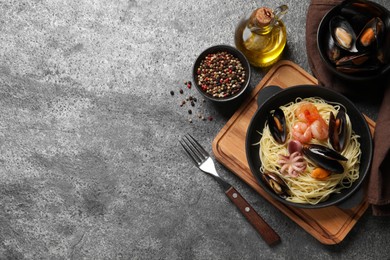 Delicious pasta with sea food served on grey table, flat lay. Space for text