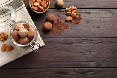 Different delicious vegan candy balls and nuts on wooden table, flat lay. Space for text