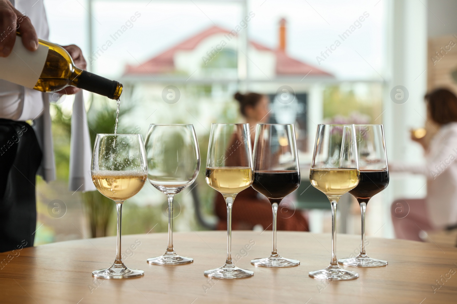 Photo of Waiter pouring wine into glass in restaurant, closeup