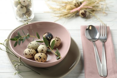 Festive Easter table setting with quail eggs and floral decor on wooden background