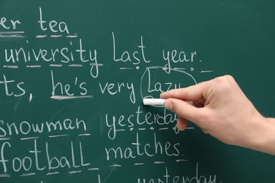 English teacher writing with chalk on green chalkboard, closeup