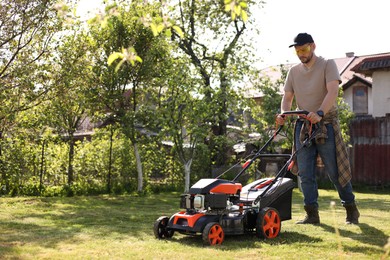 Photo of Man cutting green grass with lawn mower in garden