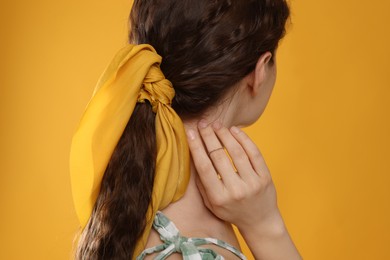 Woman with stylish bandana on yellow background
