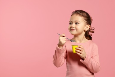 Girl with tasty yogurt on pink background. Space for text