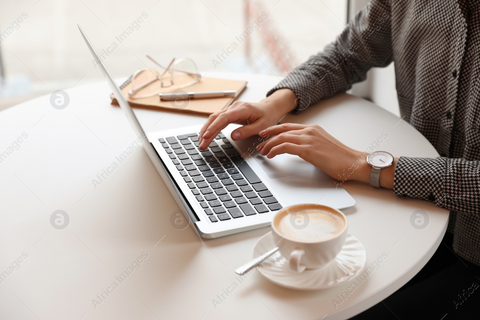 Photo of Young blogger working with laptop at table indoors, closeup