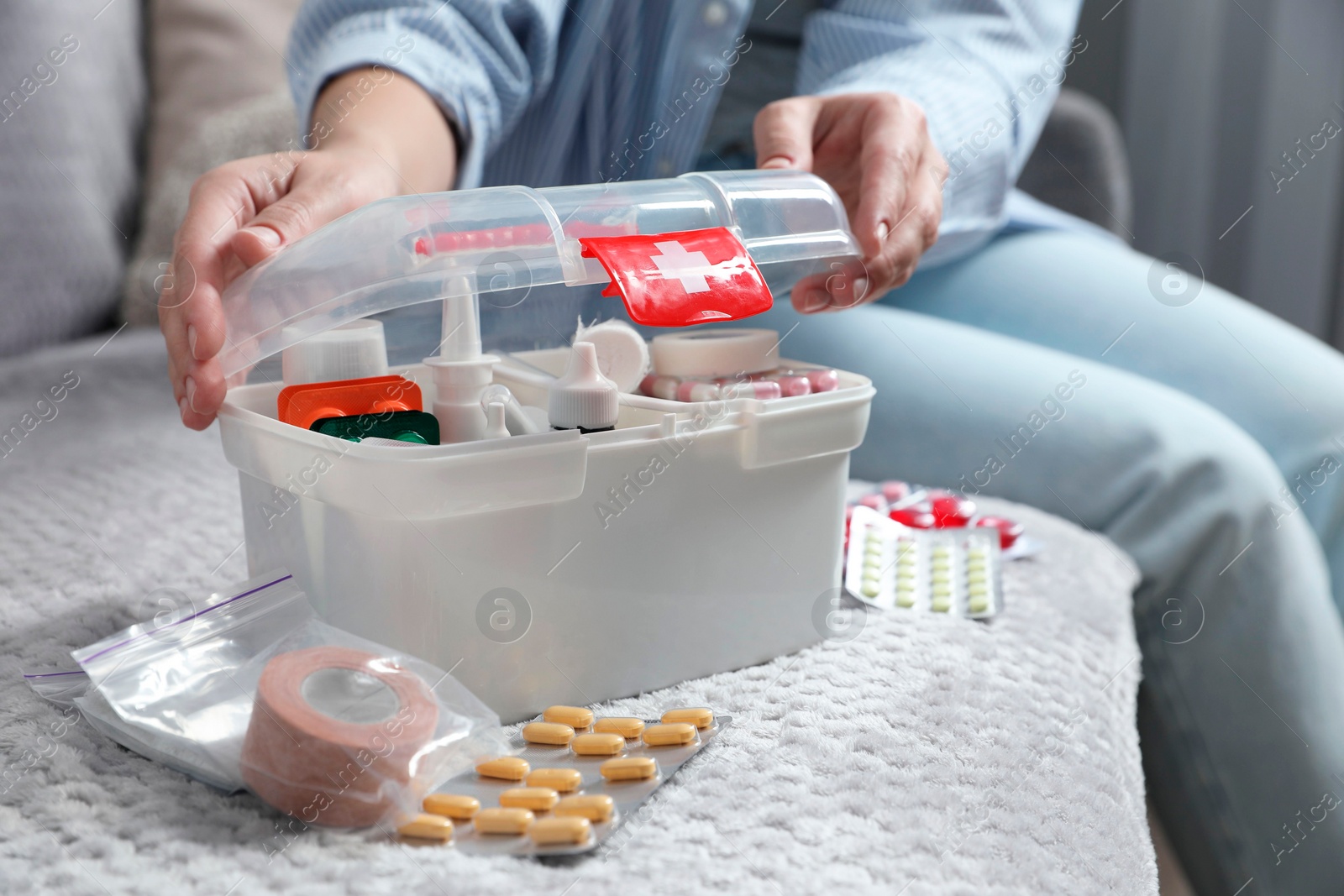 Photo of Woman opening first aid kit indoors, closeup