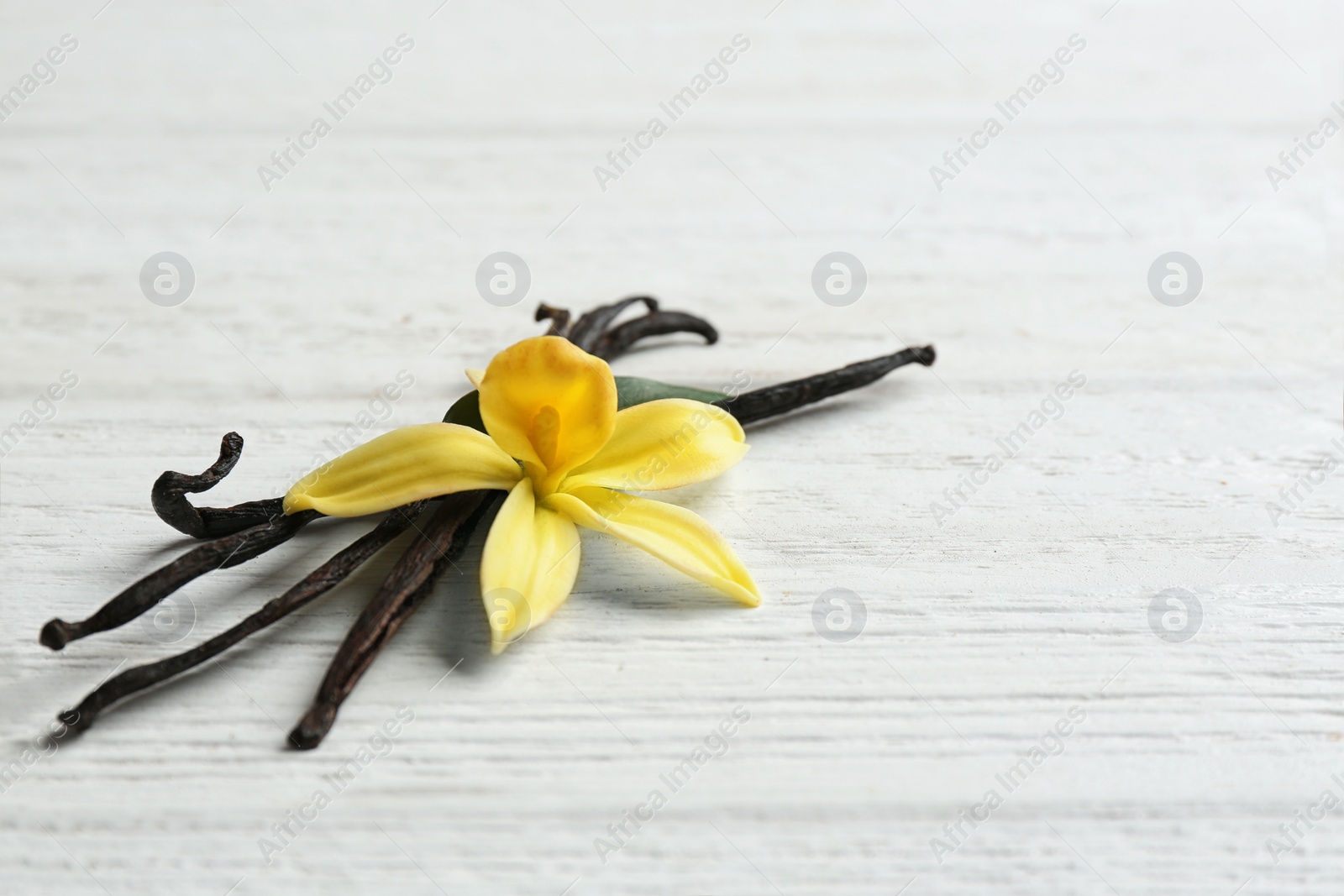 Photo of Vanilla sticks and flower on wooden background. Space for text