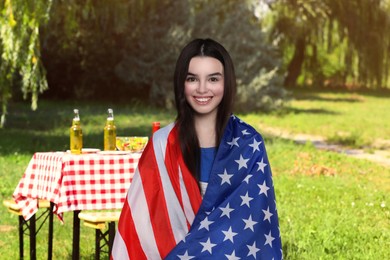 Image of 4th of July - Independence day of America. Happy girl with national flag of United States having picnic in park