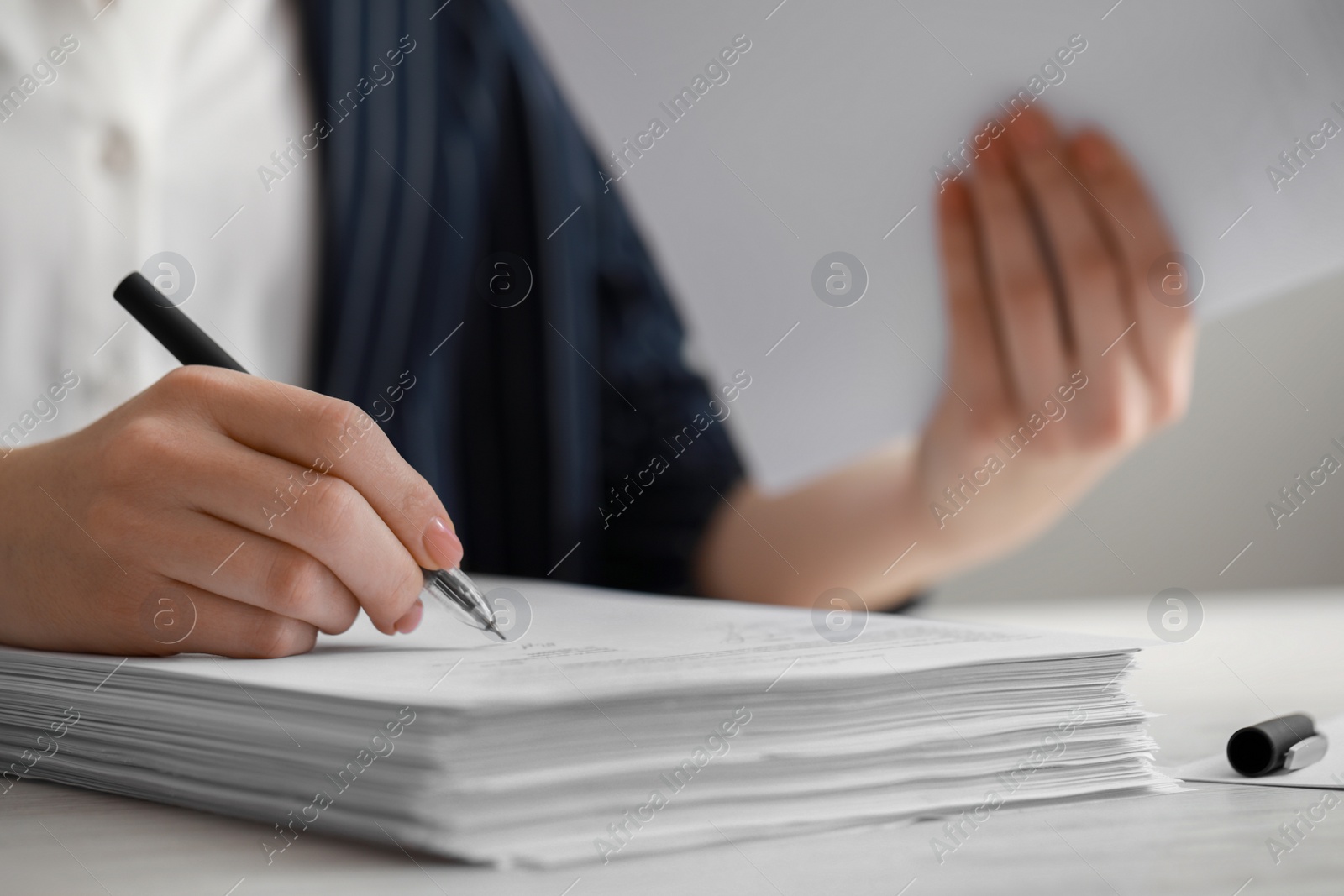 Photo of Woman signing documents at white wooden table in office, closeup. Space for text