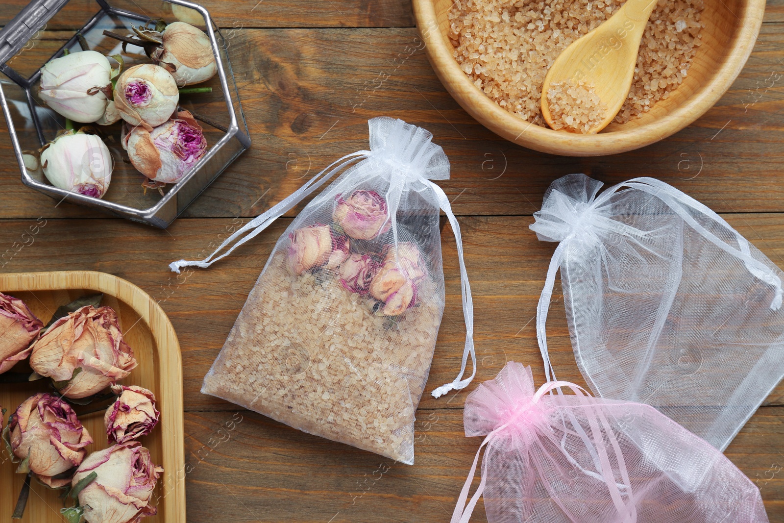 Photo of Scented sachet with dried roses and sea salt on wooden table, flat lay