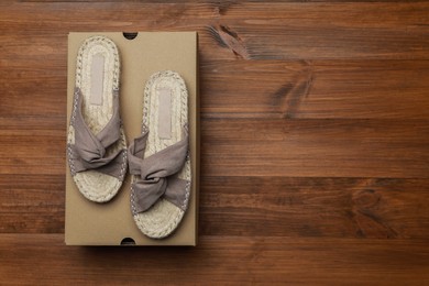 Pair of stylish shoes and cardboard box on wooden background, top view. Space for text