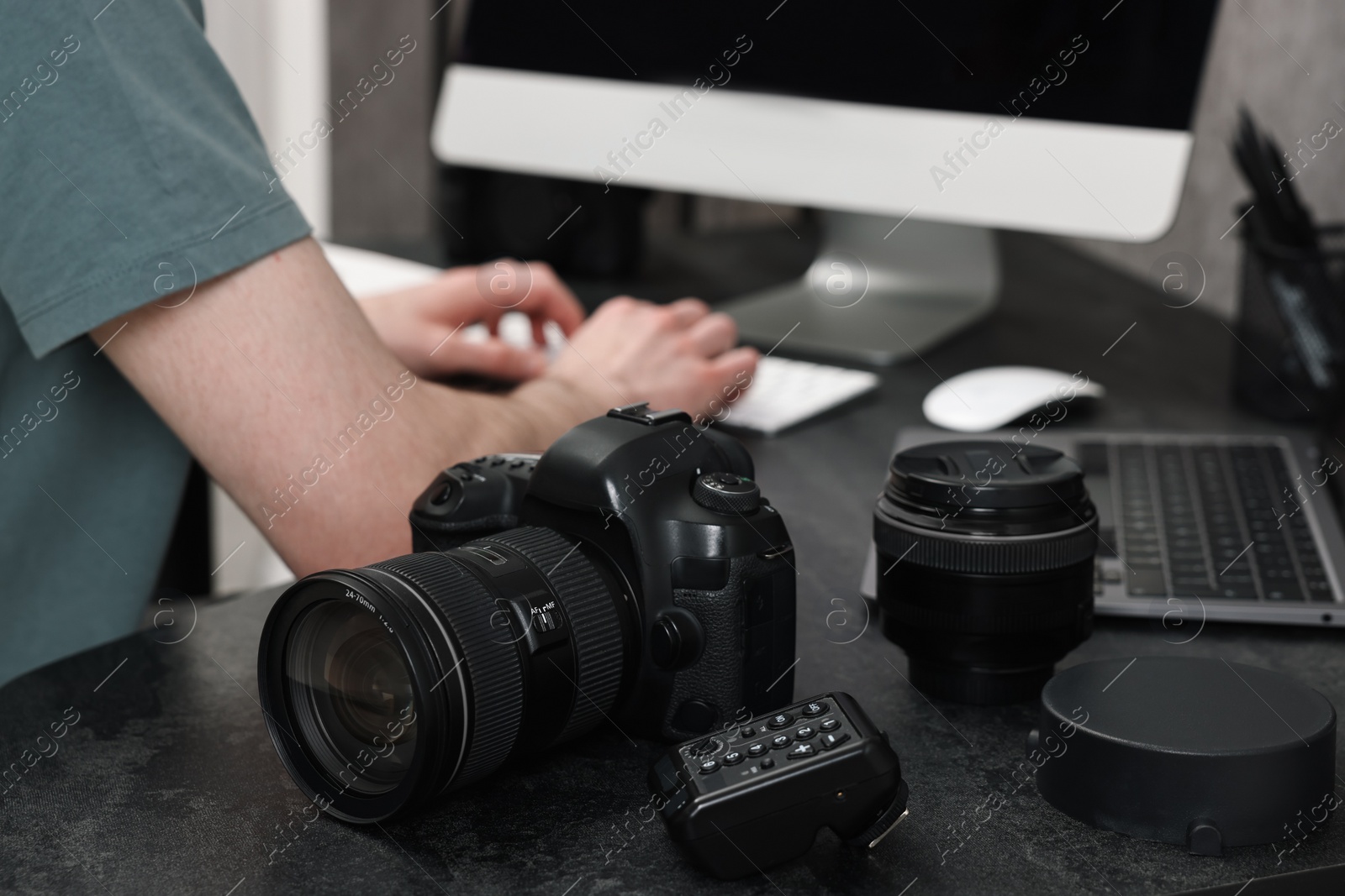 Photo of Camera on dark table, closeup. Photographer working with computer indoors, selective focus