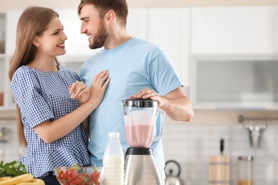 Photo of Young couple preparing delicious milk shake in kitchen