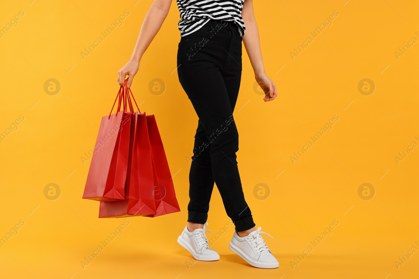 Photo of Woman with shopping bags on yellow background, closeup