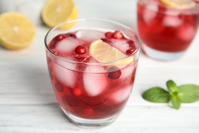 Photo of Tasty refreshing cranberry cocktail with lemon on white wooden table, closeup