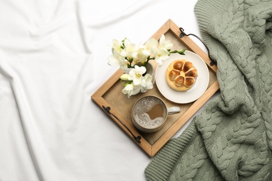 Flat lay composition with coffee and warm plaid on white bedsheet