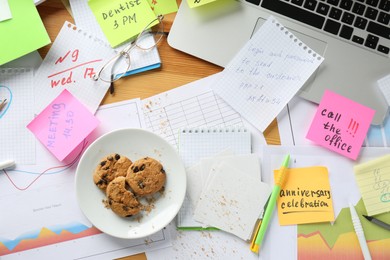 Photo of Messy table with laptop and cookies, flat lay. Concept of being overwhelmed by work