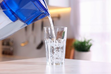 Pouring water from filter jug into glass in kitchen, closeup