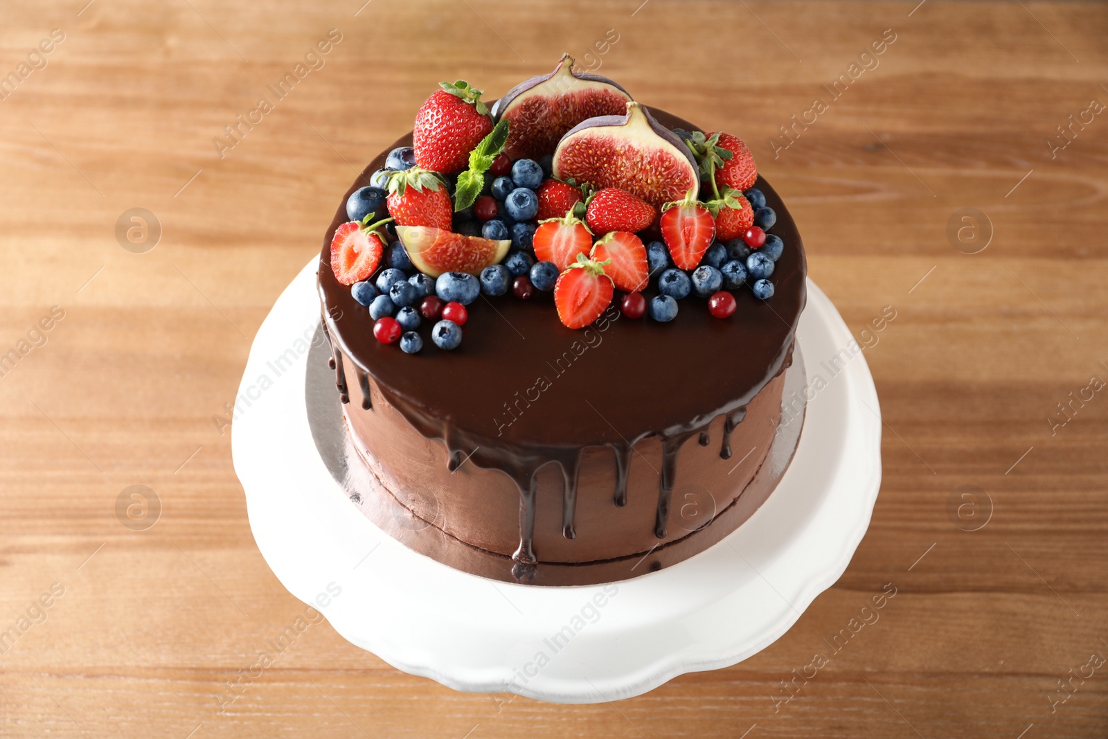 Photo of Fresh delicious homemade chocolate cake with berries on wooden table