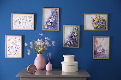 Photo of Beautiful artworks hanging on blue wall in stylish room. Interior design