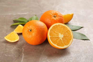 Photo of Delicious ripe oranges on grey marble table
