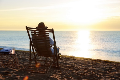 Man relaxing on deck chair at sandy beach. Summer vacation