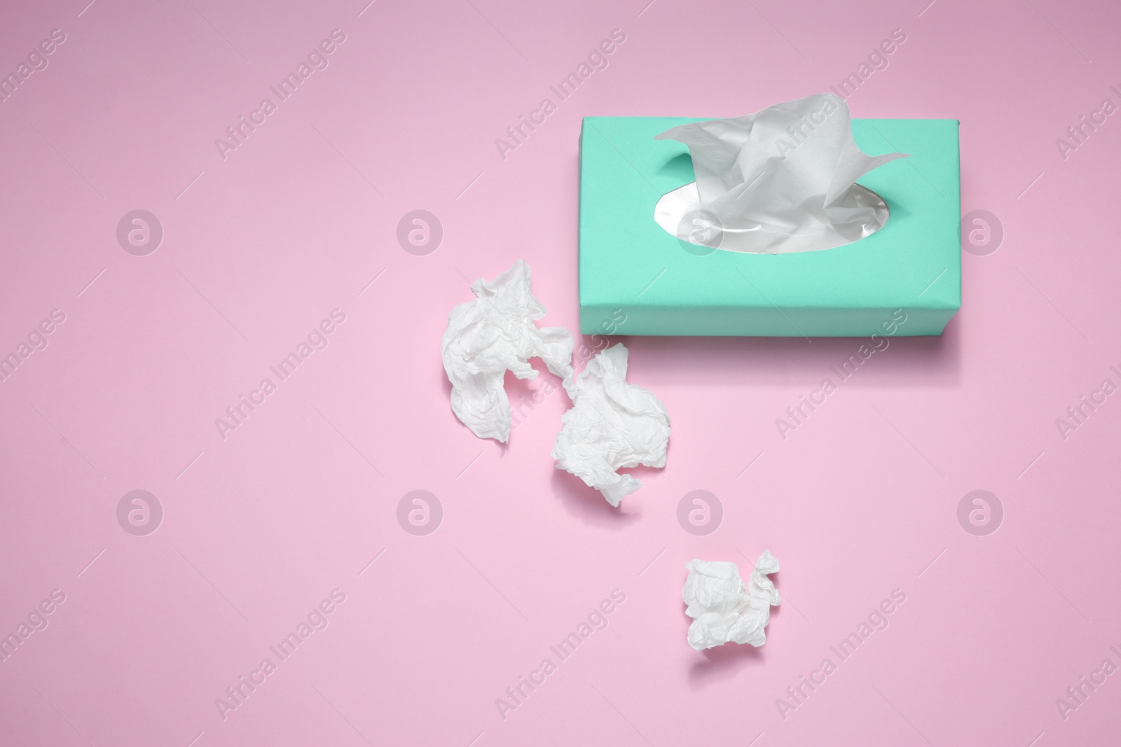 Photo of Used paper tissues and box on pink background, flat lay. Space for text